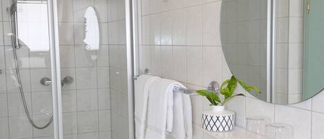 A modern bathroom with a glass-enclosed shower, a white sink, and a mirror above the sink.