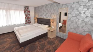 A modern hotel room with a large bed, a bedside table, a mirror, and a red sofa. - Hotel Weisses Lamm (Allersberg)