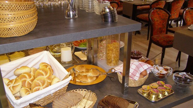 A buffet setup with various food items and utensils. - Hotel Weisses Lamm (Allersberg)