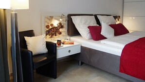 Ein modernes Hotelzimmer mit einem Bett, einem Sessel, einem Nachttisch und einer Wand mit einem Gitarren-Motiv.