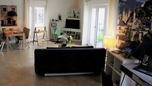 Ein modernes Wohnzimmer mit einer Couch, einem Esstisch, einem Fernseher und einem Bild an der Wand.