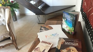 A wooden table with books and papers, a chair, and a staircase in the background. - Artemisia Sardegna (Tergu)