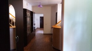 A narrow hallway with wooden flooring, a door on the left, and a staircase on the right. - Nursat Guest House (Astana)