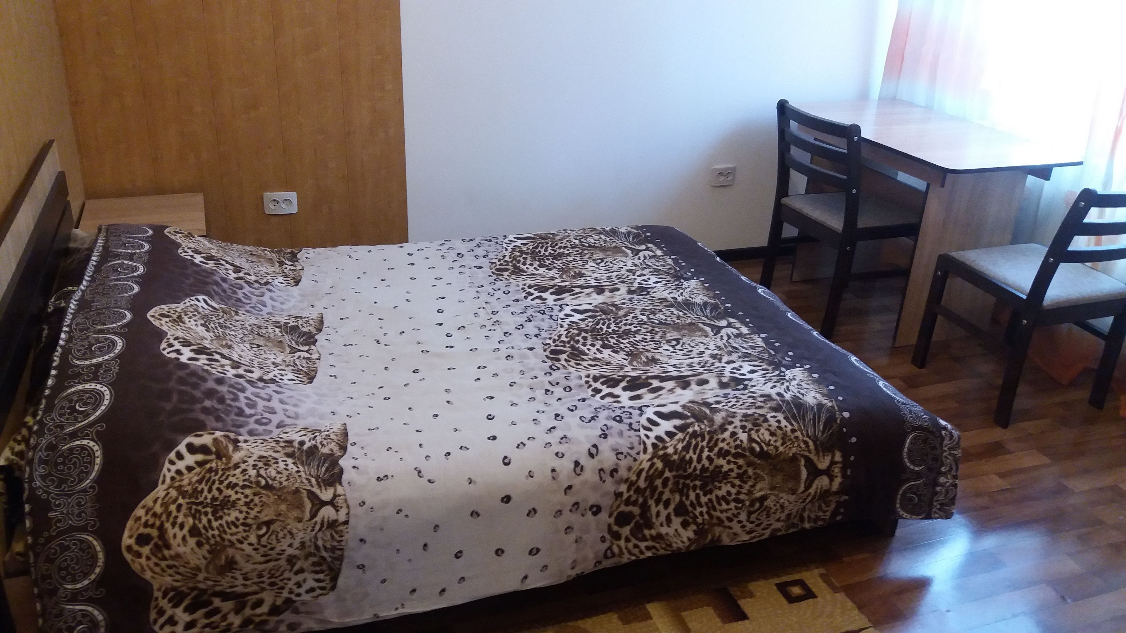 Une petite pièce comprenant un lit, un bureau et deux chaises.