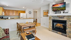 Una sala de estar moderna con chimenea, un comedor y una cocina.