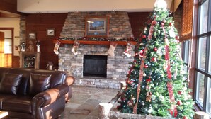 Ein gemütliches Wohnzimmer mit Kamin aus Stein, einem großen Weihnachtsbaum und Ledermöbeln.