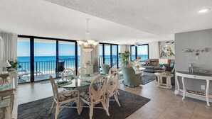 Ein geräumiges Wohnzimmer mit einem großen Glasfenster, das auf einen Balkon mit Meerblick führt.