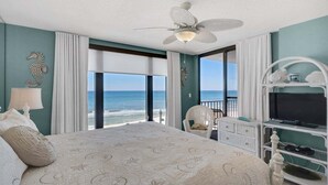 Ein Schlafzimmer mit einem großen Bett, einem Deckenventilator, einem Fernseher und Meerblick.