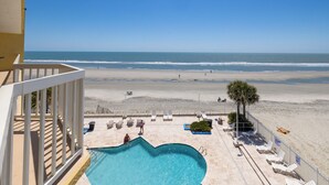 A pool with a heart-shaped design, a beach view, and a fenced area with lounge chairs. - Stay @ Sandy Pause on Folly Beach (Folly Beach)