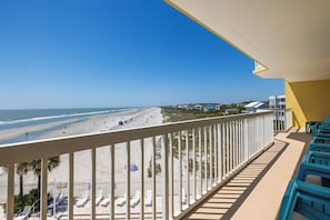 Un balcon avec vue sur la plage, des chaises longues et une rambarde.