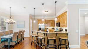 Una cocina moderna con armarios de madera, una isla central con taburetes e iluminación colgante.