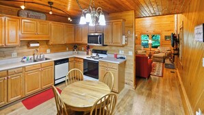 Interno di una casetta in legno con cucina, zona pranzo e soggiorno.