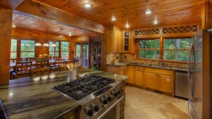 Une cuisine spacieuse avec des meubles en bois, un grand îlot central doté d’une cuisinière à gaz et un réfrigérateur.