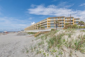 Et hotel med flere etager og balkoner, beliggende nær en sandstrand.