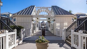 A wooden boardwalk leading to a building with a white facade and black railings. - Stay @ Serenity by the Sea on Isle of Palms (Isle of Palms)