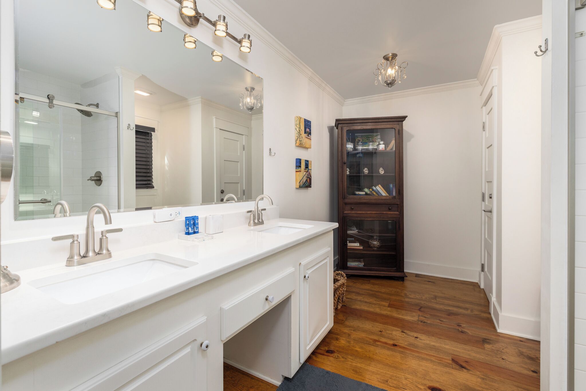 A bathroom with a double sink, a large mirror, and a cabinet with glass doors.
