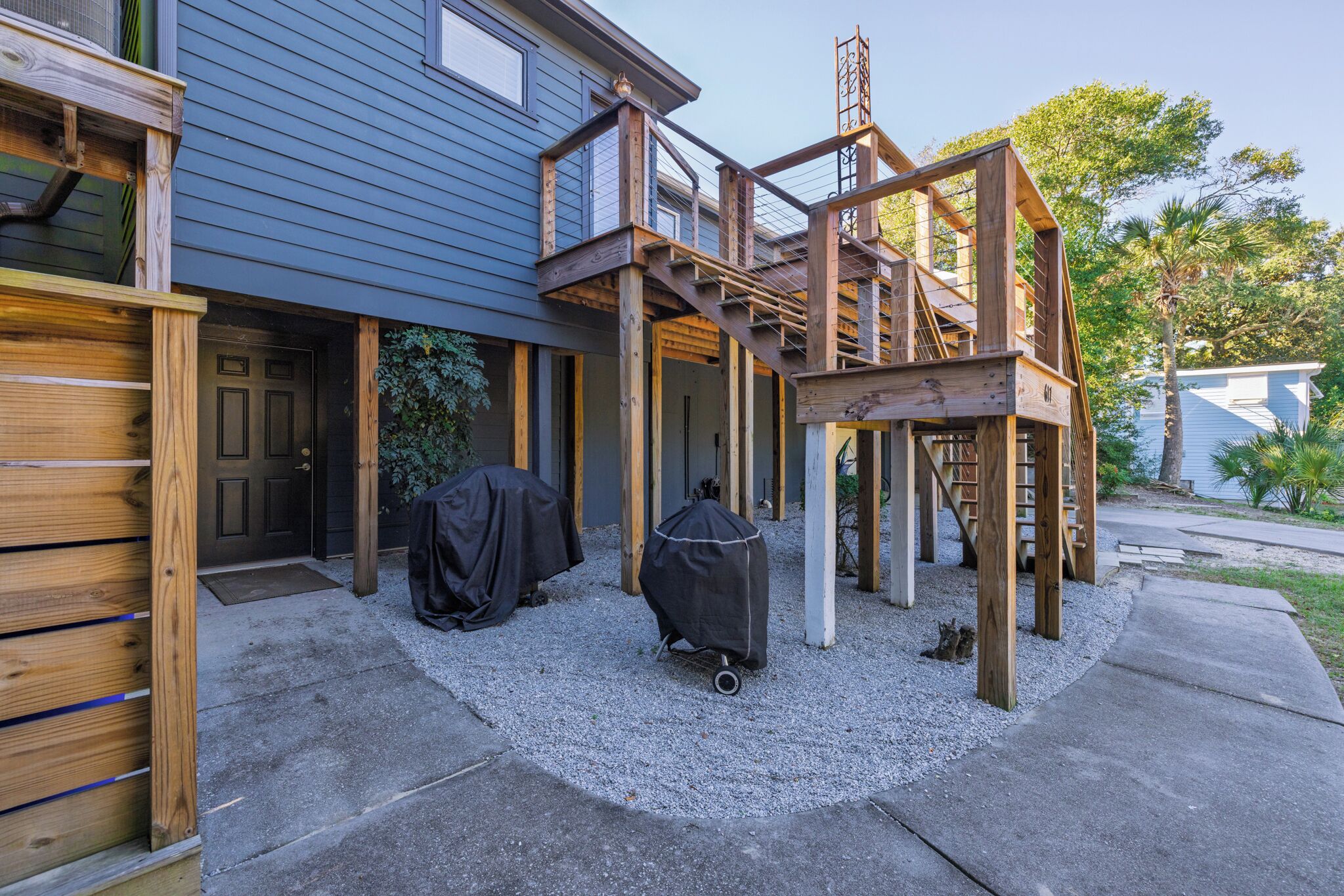 Une maison dotée d’un porche abrité, d’une terrasse en bois et d’une allée gravillonnée.