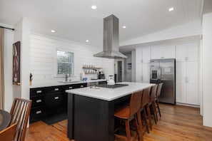 Una cocina moderna con una isla central, electrodomésticos de acero inoxidable y muebles de cocina blancos.