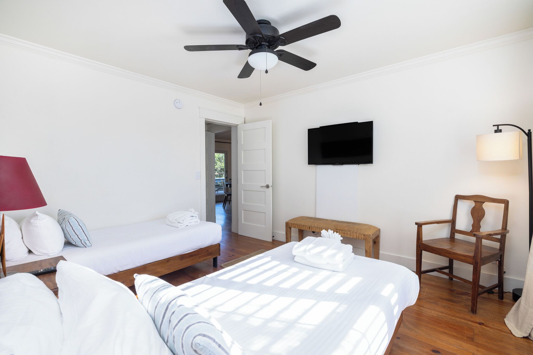 A hotel room with a bed, a chair, a TV, and a ceiling fan.