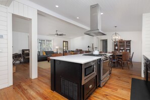 Una cocina amplia con una isla central, un comedor y una sala de estar con sofá y sillones.