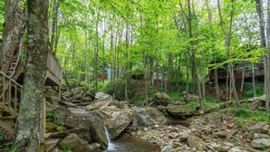 Ein bewaldetes Gebiet mit einem Bach, Holzgebäuden und einem kleinen Wasserfall.