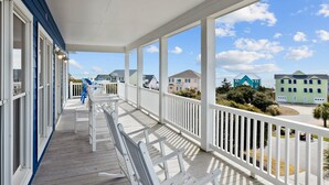 A covered porch with white railings and a view of neighboring houses. - 2nd Row Oceanview, private pool, elevator, golf cart, and easy beach access. (Emerald Isle)