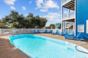 A swimming pool with blue chairs, a white fence, and a blue building with a balcony. - 2nd Row Oceanview, private pool, elevator, golf cart, and easy beach access. (Emerald Isle)