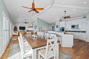 A spacious kitchen with white cabinets, a wooden dining table, and ceiling fans. - 2nd Row Oceanview, private pool, elevator, golf cart, and easy beach access. (Emerald Isle)