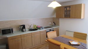 Een praktische keuken met een magnetron, koffiezetapparaat, spoelbak en een eethoek met een tafel en stoelen.