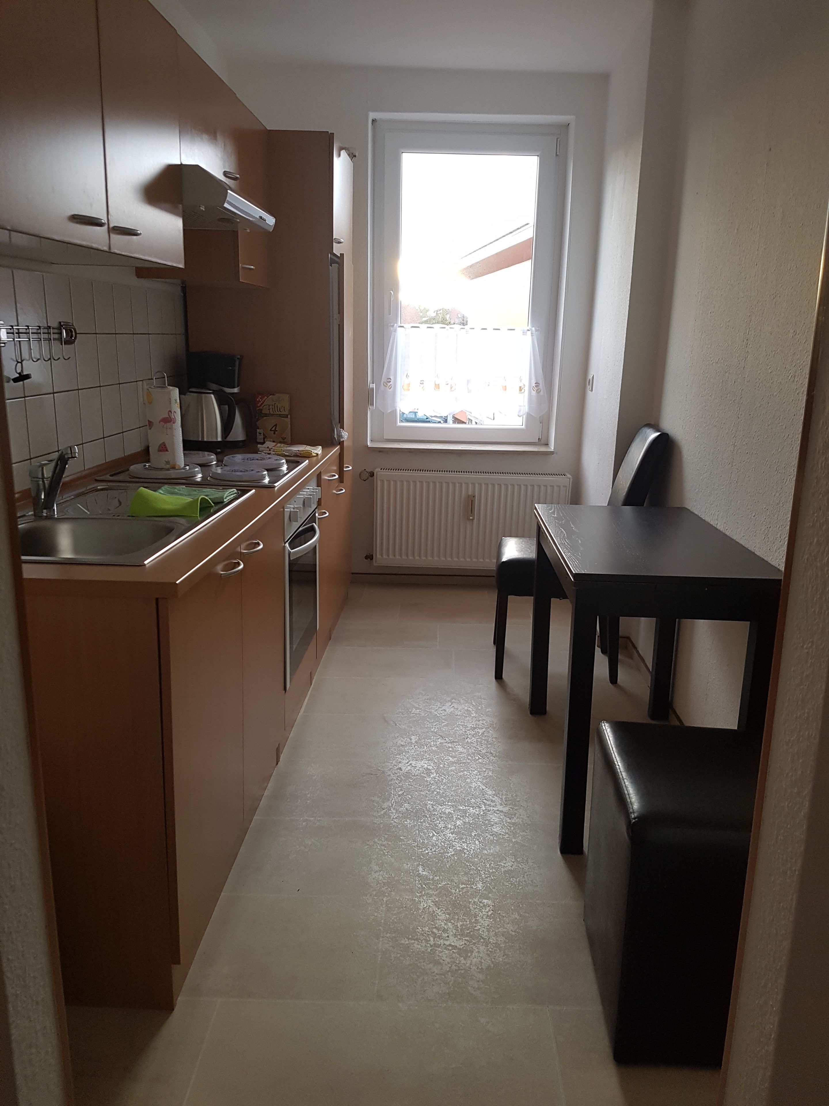 A compact kitchen with a window, a sink, a stove, and a dining table.