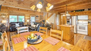 L’intérieur chaleureux d’un chalet en bois comprend un coin repas, une cuisine et un salon.