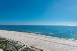 A beach with a clear sky, calm sea, and a sandy shore.