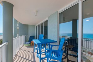 A balcony with a table and chairs, a small table with a bottle, and a view of the ocean. - Oceanfront escape! Relax in this cozy 1BR condo at Panama City Beach. FREE BEACH CHAIRS! (Panama City Beach)
