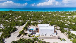 A modern beach house with a pool, surrounded by lush greenery and a clear view of the ocean. - Aqueous: Luxury Villa w/Tranquil Pool Near Beach (Leeward Settlement)