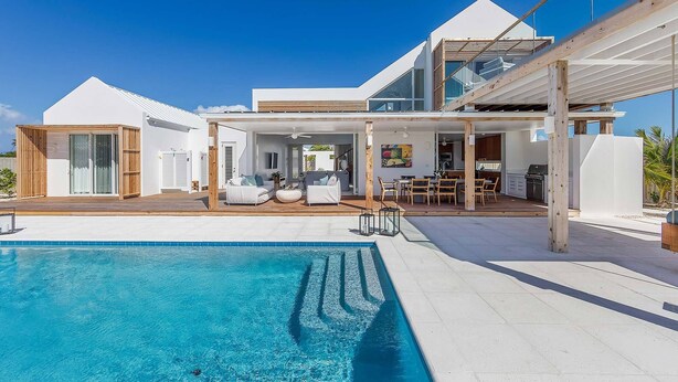 A modern house with a swimming pool, outdoor seating, and a covered patio. - Aqueous: Luxury Villa w/Tranquil Pool Near Beach (Leeward Settlement)