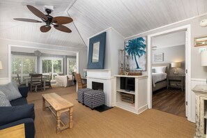A spacious living room with a fireplace, a ceiling fan, and a view of the outside.