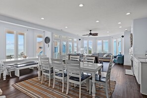 A spacious kitchen with a dining area, large windows, and a ceiling fan. - Pet Friendly,Oceanfront,private pool,beach boardwalk,located in Spinnakers Reach (Emerald Isle)