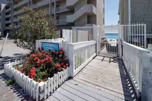 Entrada cerrada a una zona de playa privada con muelle de madera y un cartel que indica acceso a la playa.