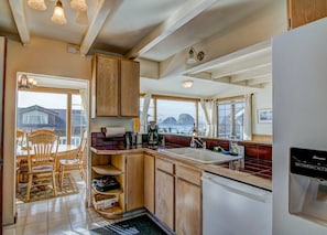 A kitchen with wooden cabinets, a sink, and a refrigerator. - Beach Treasure- Ocean view~ Oceanside (Oceanside)