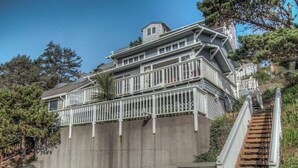 A multi-story house with a wooden staircase leading to a balcony.
