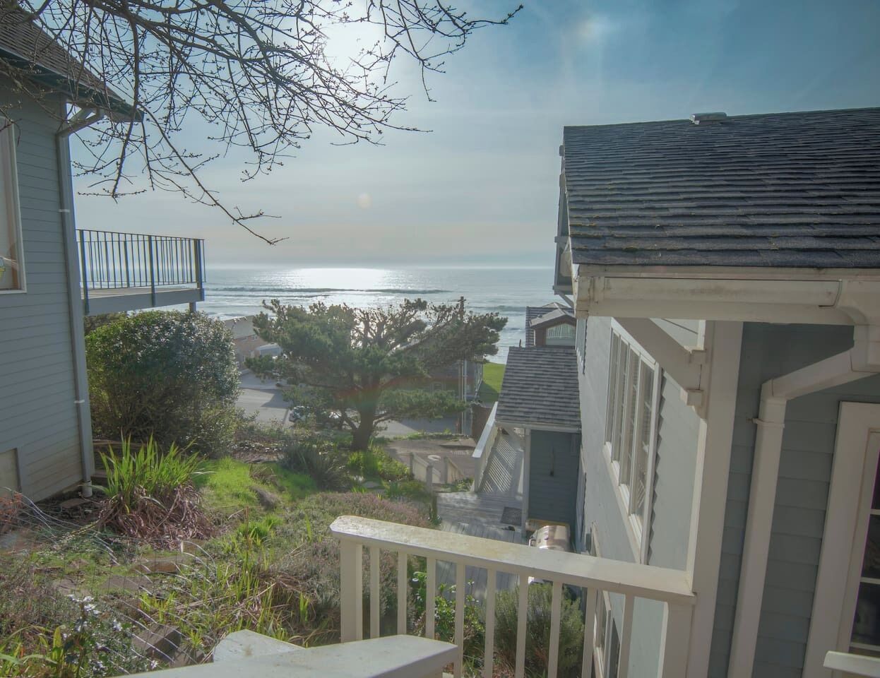 A residential area with a view of the ocean, a balcony, and a tree.