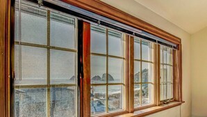 A room with a large window overlooking a rocky coastline.