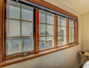 A room with a large window overlooking a rocky coastline. - Beach Treasure- Ocean view~ Oceanside (Oceanside)