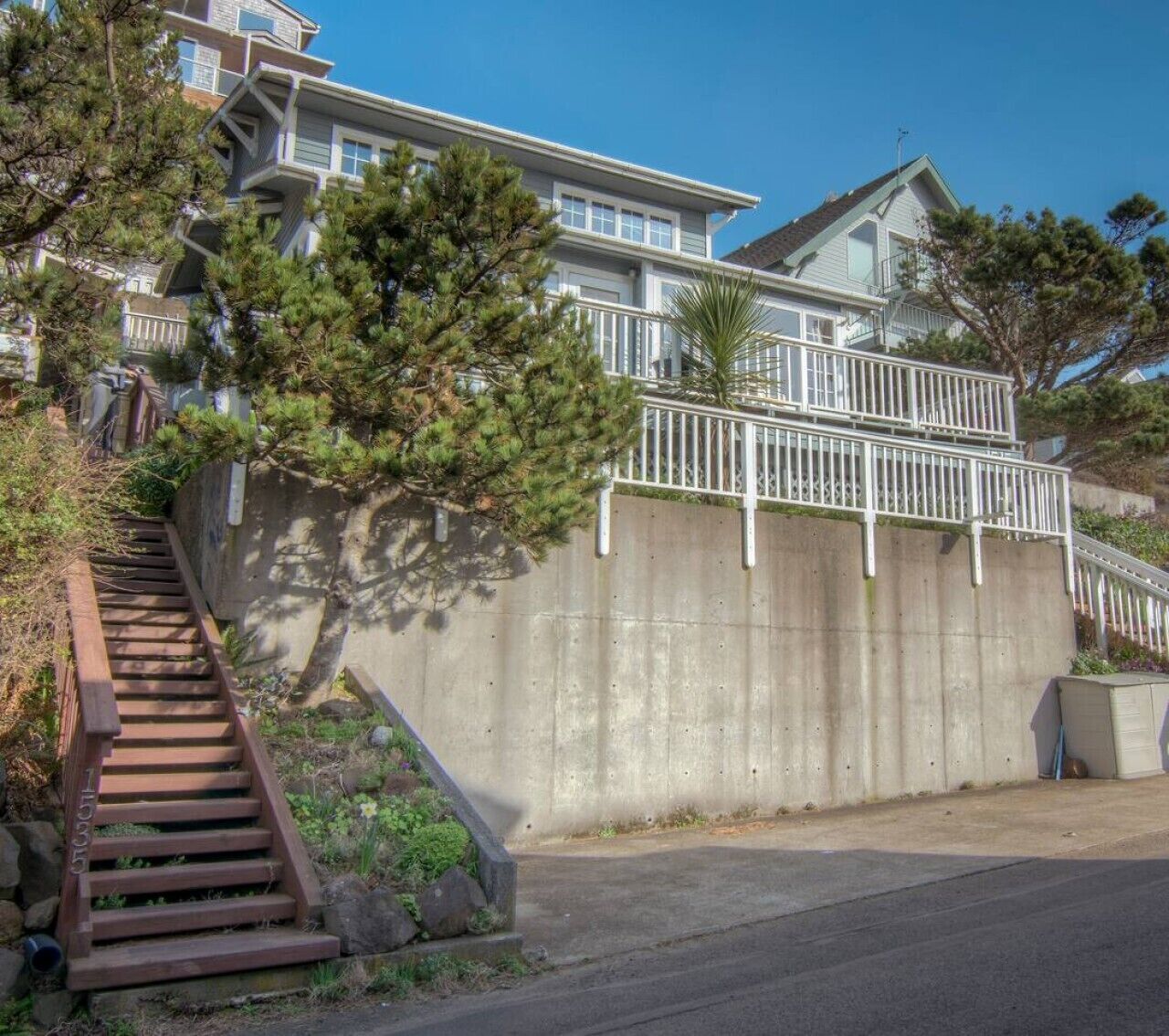 A two-story house with a concrete retaining wall, a wooden staircase, and a balcony.