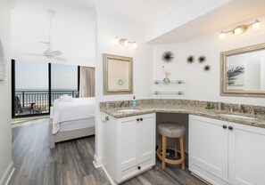 A hotel room with a balcony, a bed, a bathroom with a vanity, and a large mirror.