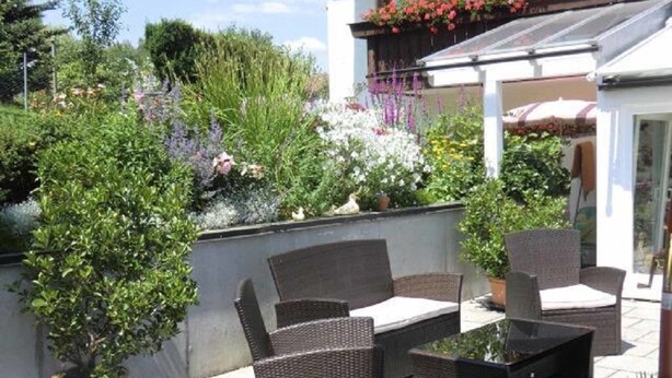 Eine Terrasse im Freien mit Korbmöbeln und Topfpflanzen.