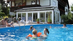 Ein Schwimmbeckenbereich mit Liegestühlen und einer überdachten Sitzgelegenheit.