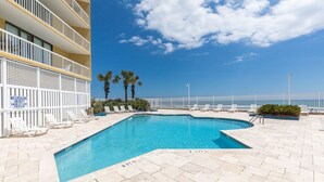 Une piscine entourée d’un ciel d’un bleu éclatant, de palmiers et d’une clôture blanche.