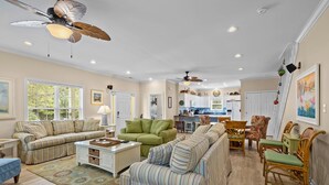 A spacious living room with striped sofas, a coffee table, and a dining area with wicker chairs.