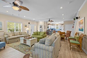 Relax in this spacious living room with a high ceiling, ceiling fan, and comfortable seating area.